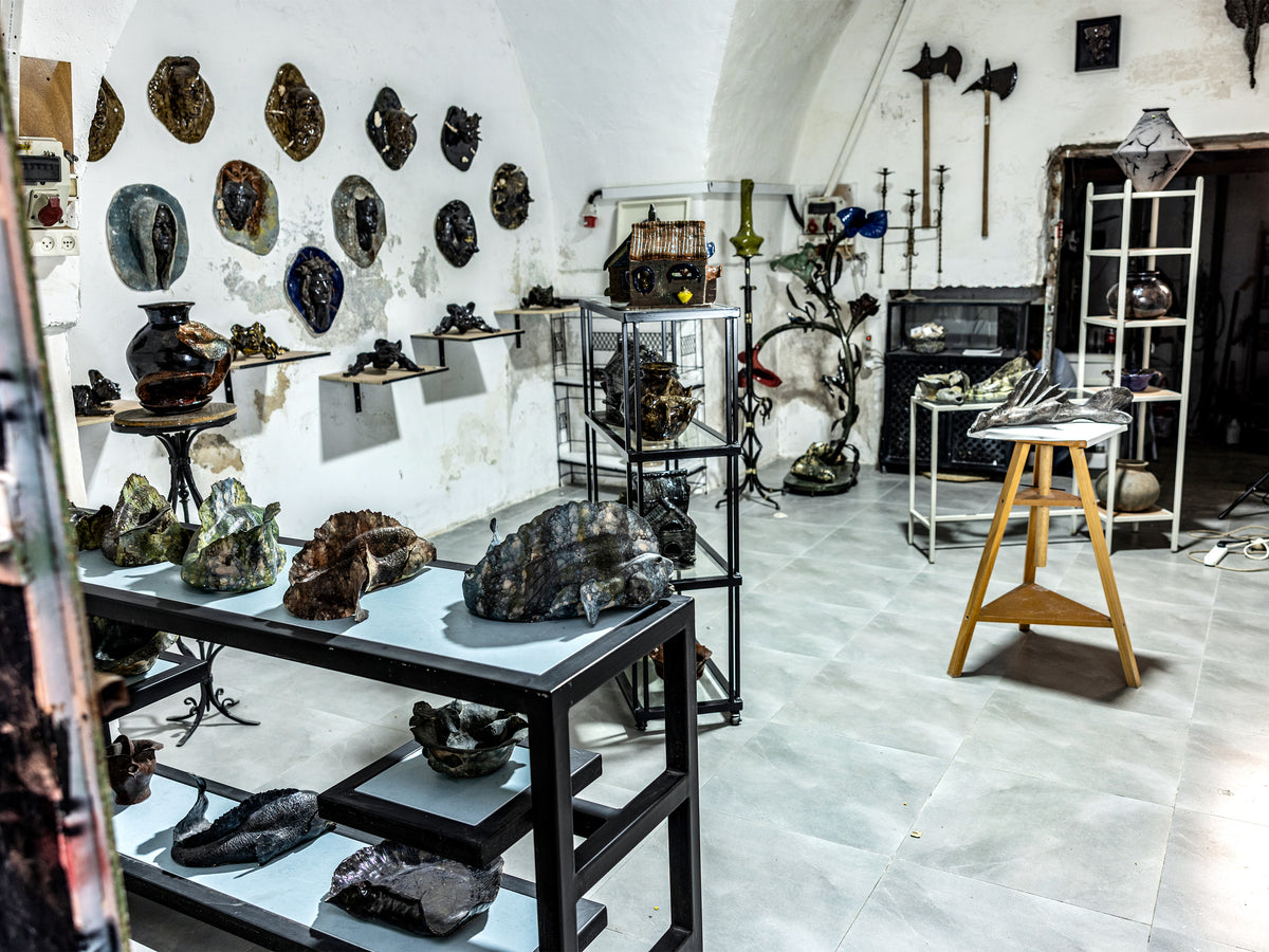 A rustic, gothic-style room filled with various mineral specimens, fossils, and dark metal artifacts displayed on tables, shelves, and the walls.