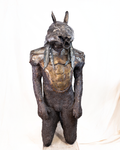A life-sized figurative sculpture of a human figure crowned with a rat's skull, forged, wrought, and welded by hand from dark iron with a rough, deeply tactile, erupting surface, standing against a plain background.