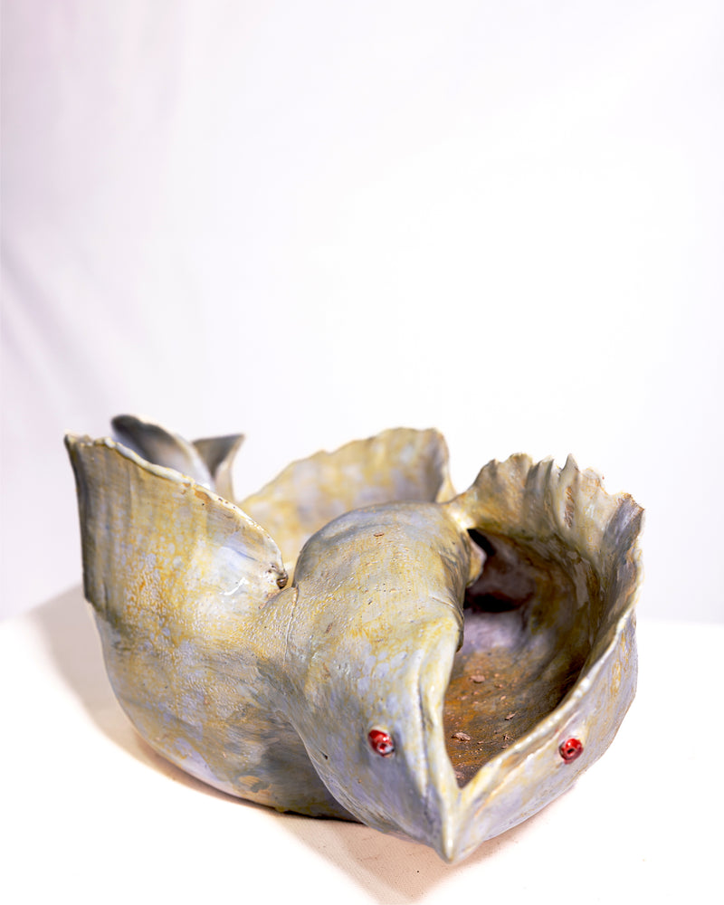 A sculptural ceramic bird bowl with a textured, rustic finish in muted gray, beige, and brown tones, accented with small red details, photographed on a white background.